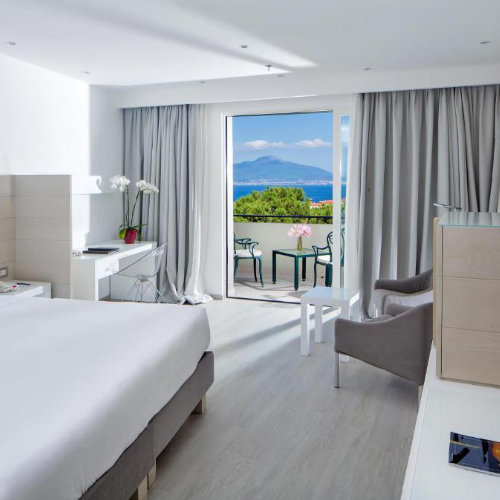 Chambre lumineuse du Hilton Sorrento Palace avec balcon et vue sur la mer.