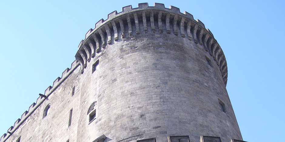 Tour du Castel Nuovo à Naples vue de près, avec murailles en pierre et architecture médiévale.