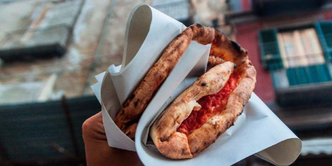Une main tenant une authentique pizza napolitaine pliée en quatre, a portafoglio.