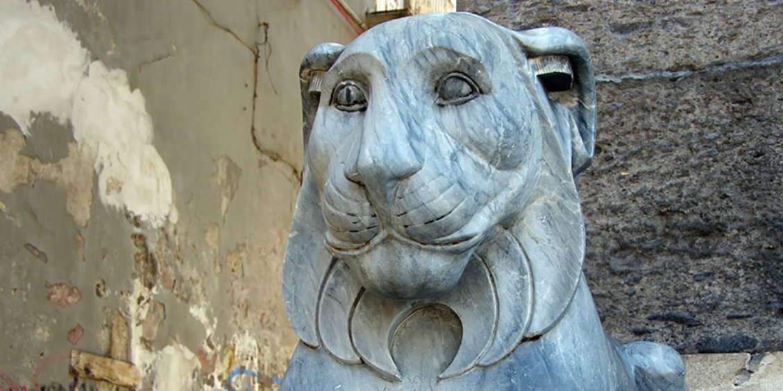 Statue de lion en pierre sur la place du Plébiscite à Naples, détail sculptural historique.