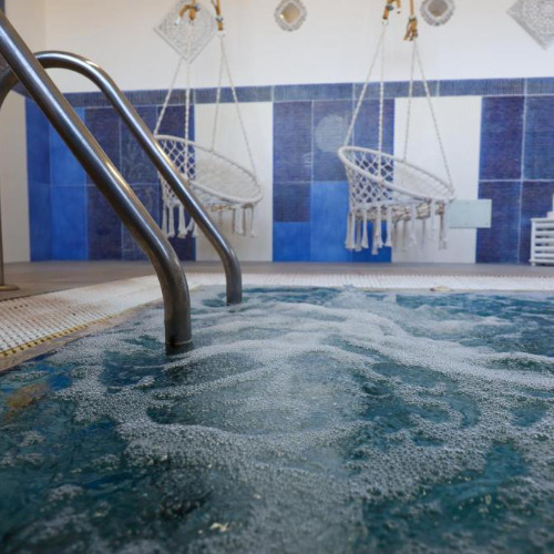 Espace spa avec jacuzzi et fauteuils suspendus.