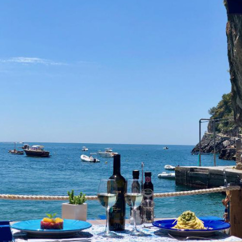 Table dressée en bord de mer avec spécialités italiennes et vin blanc au restaurant de l'hôtel.