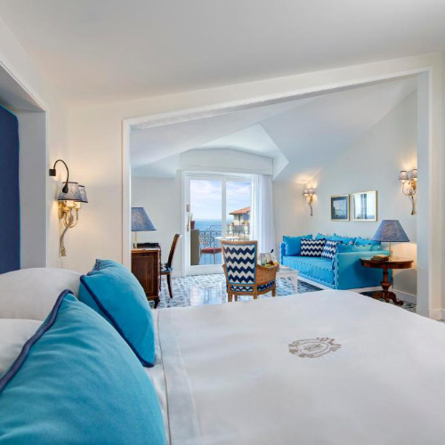 Chambre de l’Hotel Ambasciatori à Sorrente avec salon et vue sur la mer.
