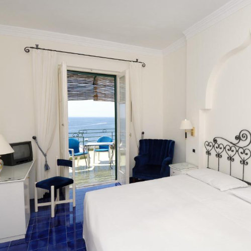 Chambre lumineuse de l’Hotel Aurora à Amalfi avec balcon vue mer.