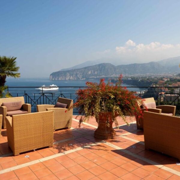 Terrasse de l’Hotel Bristol à Sorrente avec salons extérieurs, fleurs et vue sur le golfe.