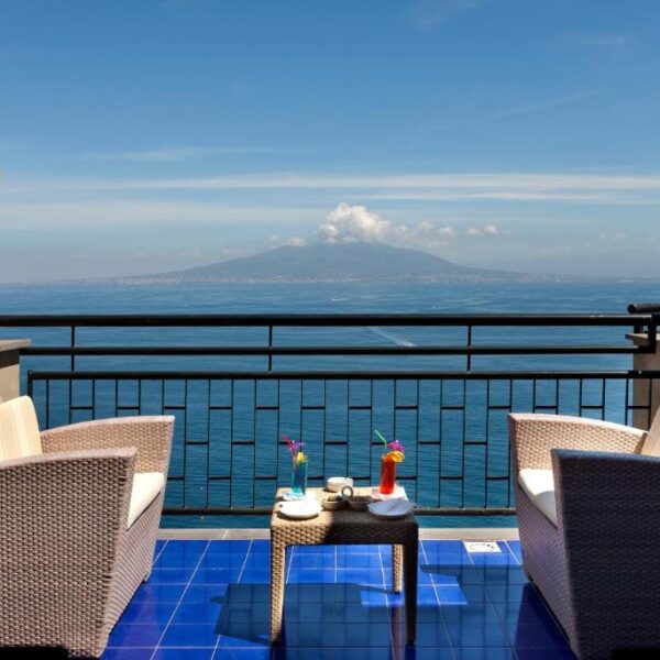 Espace lounge de l’Hotel Bristol à Sorrente avec fauteuils, cocktails et vue sur le Vésuve.