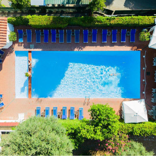 Piscine de l’Hotel Central à Sorrente vue d’en haut avec transats bleus et jardin.