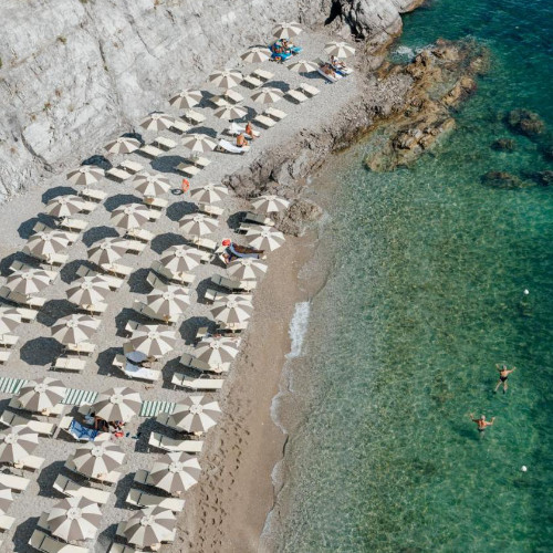 Plage privée de l'Hôtel Cetus avec parasols et eaux cristallines vue de dessus.