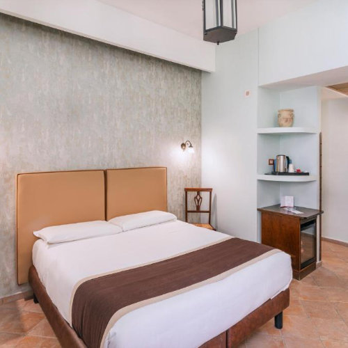 Chambre double lumineuse de l'Hôtel Convento à Naples, avec décor sobre, mobilier en bois et sol traditionnel.