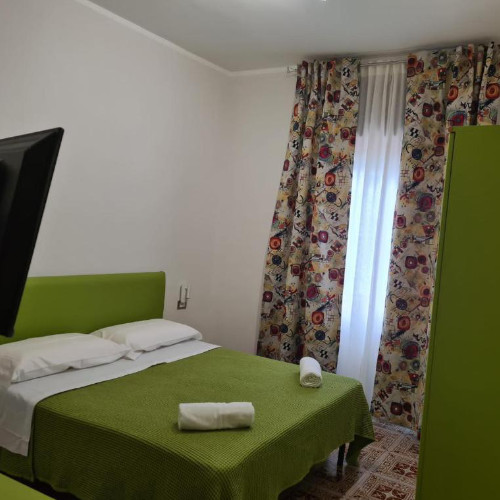 Chambre de l'Hôtel Dalì avec décoration vert pomme et rideaux à motifs.