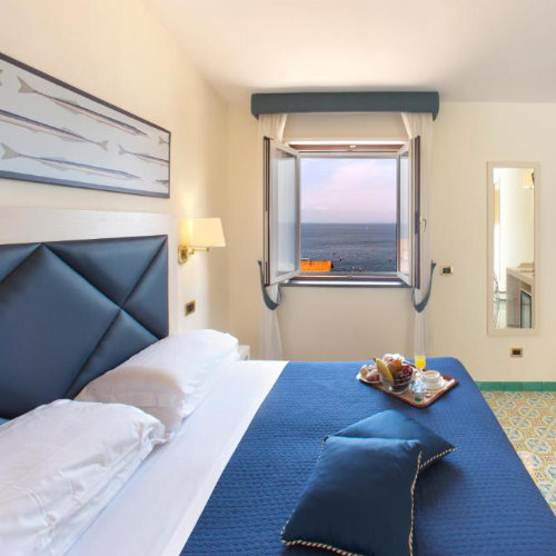 Chambre de l’Hotel Del Mare à Sorrente avec lit double, fenêtre et vue sur la mer.