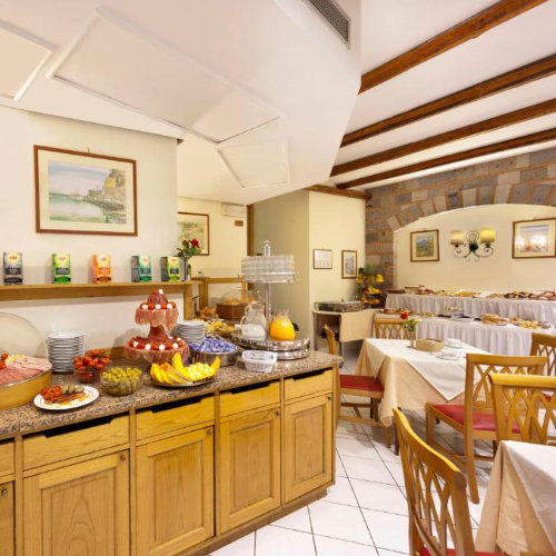 Salle du petit-déjeuner de l’Hotel Del Mare à Sorrente avec buffet, tables et poutres apparentes.