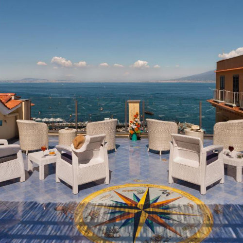 Terrasse panoramique de l’Hotel Del Mare à Sorrente avec fauteuils blancs et vue sur le golfe.