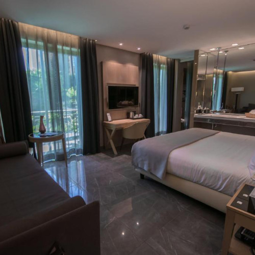 Chambre d'hôtel moderne et élégante avec un lit spacieux, un coin salon et de grandes fenêtres à l'Hôtel Forum.