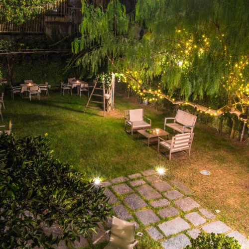 Espace de détente extérieur dans le jardin de l'hôtel, éclairé par des guirlandes lumineuses en soirée.