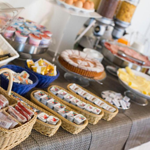 Buffet de petit-déjeuner varié avec des gâteaux, des yaourts, des céréales et des paniers de produits emballés.