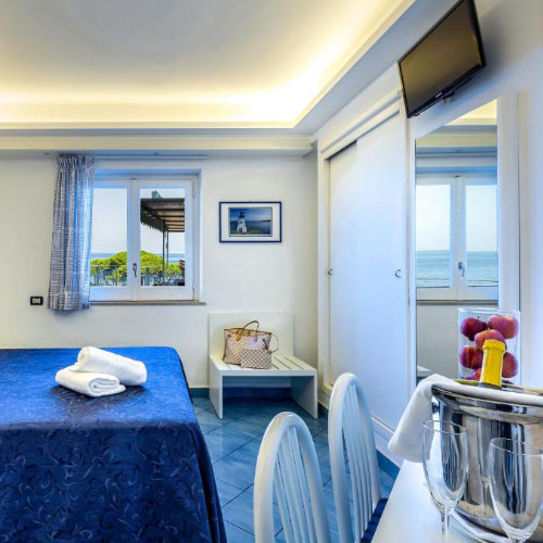Chambre de l’Hotel Il Faro à Sorrente avec décoration bleue et vue sur la mer.