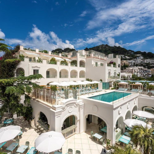 Vue extérieure de l'Hôtel La Palma à Capri avec sa piscine en terrasse, ses arches blanches et son décor méditerranéen.