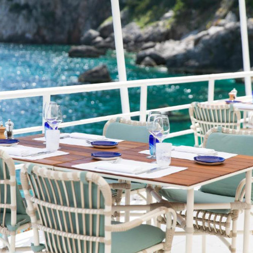 Table dressée au restaurant de l'Hôtel La Palma à Capri offrant une vue imprenable sur la mer turquoise.