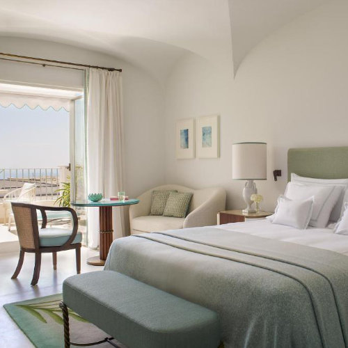 Chambre élégante de l'Hôtel La Palma à Capri avec décoration vert pastel, lit spacieux et balcon vue mer.