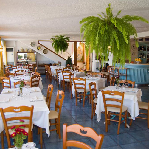 Restaurant de l’Hotel La Primavera à Massa Lubrense avec tables dressées et bar.