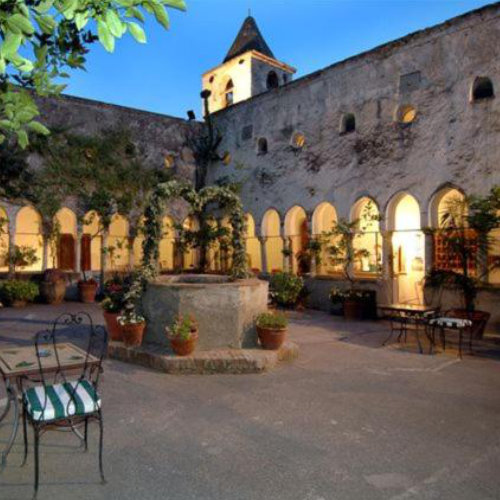 Cloître historique de l’Hotel Luna Convento à Amalfi illuminé le soir.