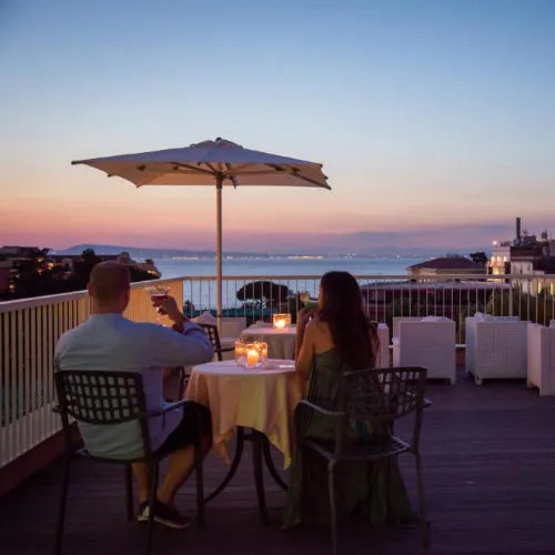 Terrasse panoramique de l’Hotel Michelangelo à Sorrente avec dîner au coucher du soleil.