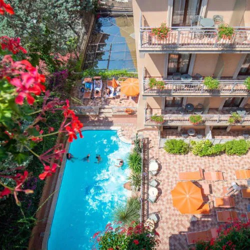 Piscine de l’Hotel Michelangelo à Sorrente avec transats et balcons fleuris.