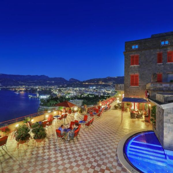 Terrasse de l’Hotel Minerva à Sorrente le soir avec piscine illuminée et vue sur le golfe.