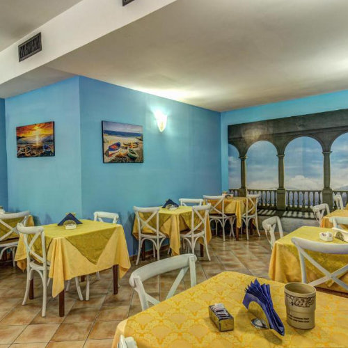 Salle du petit-déjeuner de l’Hotel Nice à Sorrente avec tables jaunes et décoration bleue.