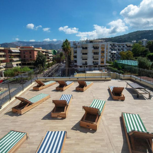 Terrasse solarium de l’Hotel Nice à Sorrente avec transats et vue sur les collines.