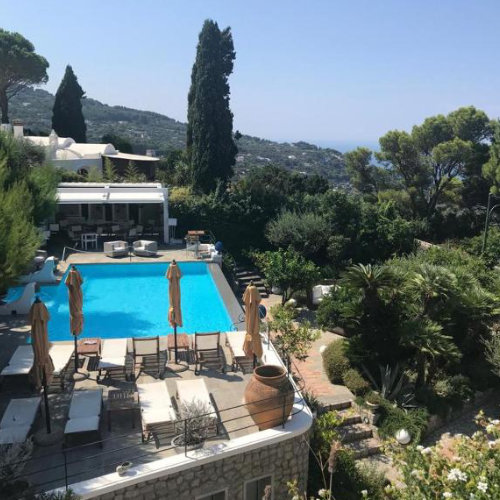 Piscine de l'hôtel Orsa Maggiore à Capri entourée de végétation luxuriante avec vue sur la mer.