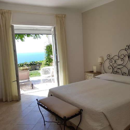 Chambre de l'hôtel Orsa Maggiore à Capri avec lit en fer forgé et balcon ouvert sur la mer.
