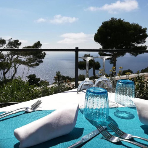 Table dressée sur la terrasse de l'hôtel Orsa Maggiore à Capri avec vue panoramique sur la mer.