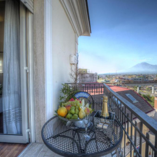 Balcon de l'Hôtel Palma avec corbeille de fruits, champagne et vue sur le Vésuve.