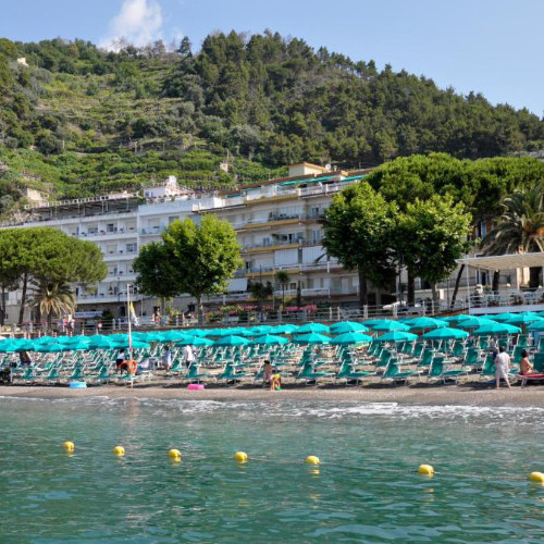 Plage privée de l'hôtel avec ses rangées de parasols turquoises face au front de mer.