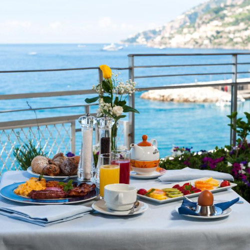 Petit-déjeuner complet servi en terrasse avec vue panoramique sur la côte à Maiori.