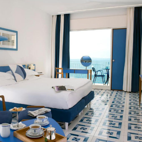 Chambre de l’Hotel Parco dei Principi à Sorrente avec balcon et décoration bleue.