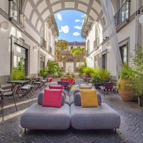 Cour intérieure de l’Hotel Piazza Bellini à Naples avec espace détente et architecture élégante.