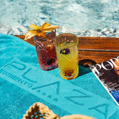 Cocktails au bord de la piscine de l’Hotel Plaza Sorrento avec serviette turquoise.