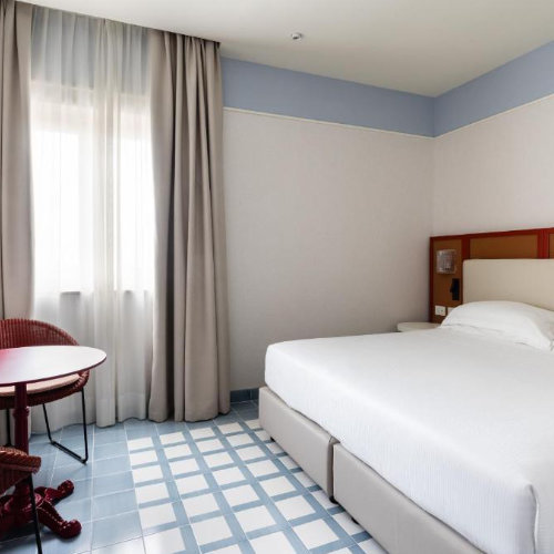 Chambre moderne de l’Hotel Plaza Sorrento avec lit double et décoration claire.