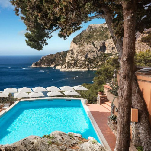 Piscine de l'hôtel Punta Tragara à Capri avec vue panoramique sur la mer et les falaises.