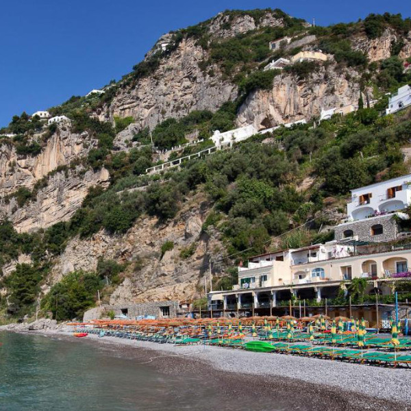 Plage devant l’Hotel Pupetto à Positano avec transats colorés et falaises.