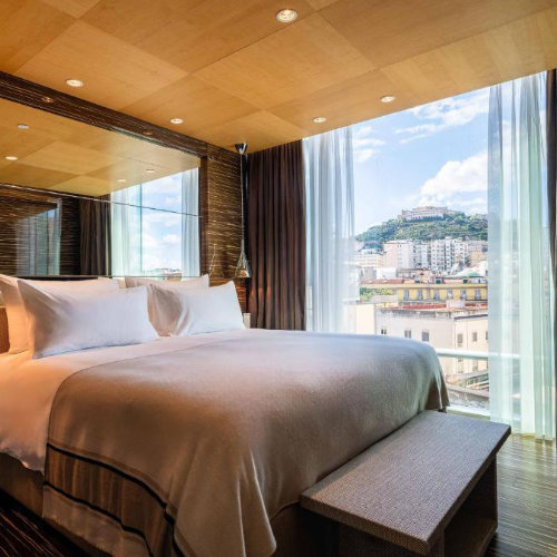 Chambre design de l’Hotel Romeo à Naples avec vue sur la ville et intérieur moderne.
