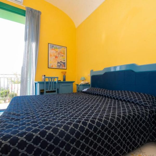 Chambre lumineuse aux couleurs vives pour un séjour typique à l'Hôtel Savoia.