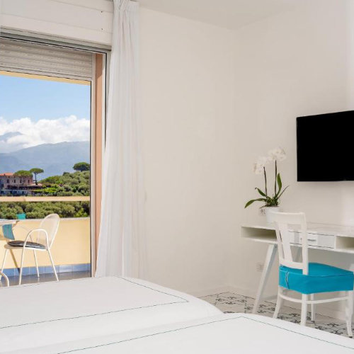 Chambre de l’Hotel Vesuvio à Sorrente avec balcon, bureau et décoration claire.