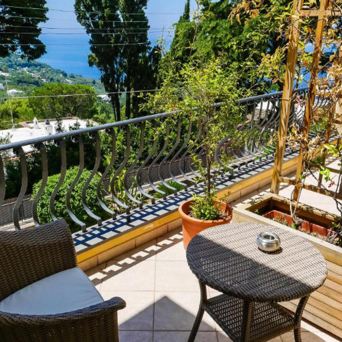 Terrasse de l'Hôtel Villa Ceselle à Capri avec fauteuil en osier et vue panoramique sur la mer et la nature.