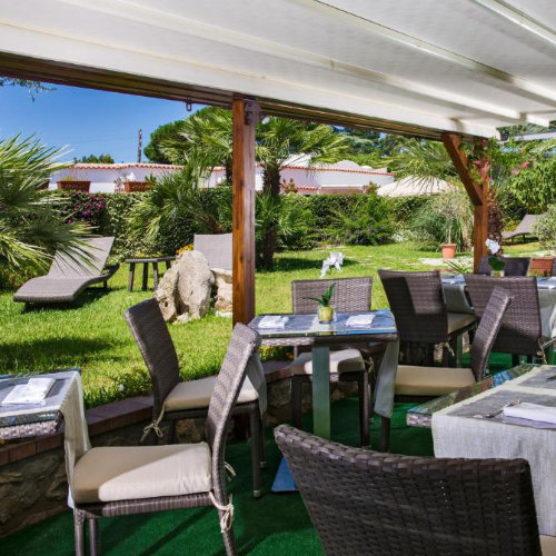 Terrasse du restaurant de l'Hôtel Villa Ceselle à Capri avec tables en osier et jardin ensoleillé.