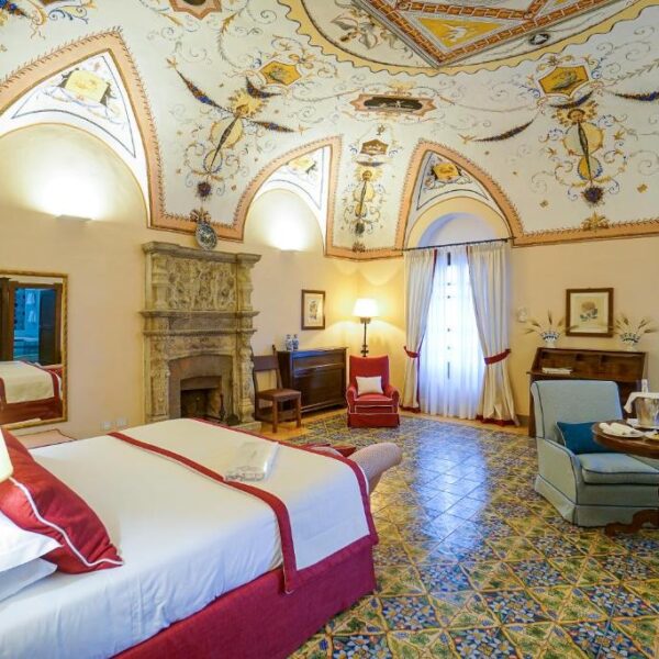 Chambre élégante de l’hôtel Villa Cimbrone à Ravello avec plafond décoré et mobilier ancien.