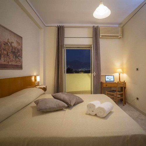 Chambre double confortable avec bureau et balcon ouvert offrant une vue nocturne sur les environs de Pompéi.